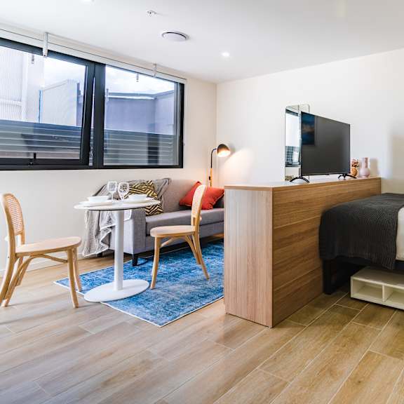 a bedroom with a bed and a desk and a window