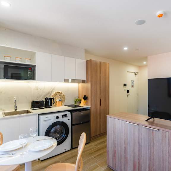 a kitchen and dining area with a washer and dryer and a television