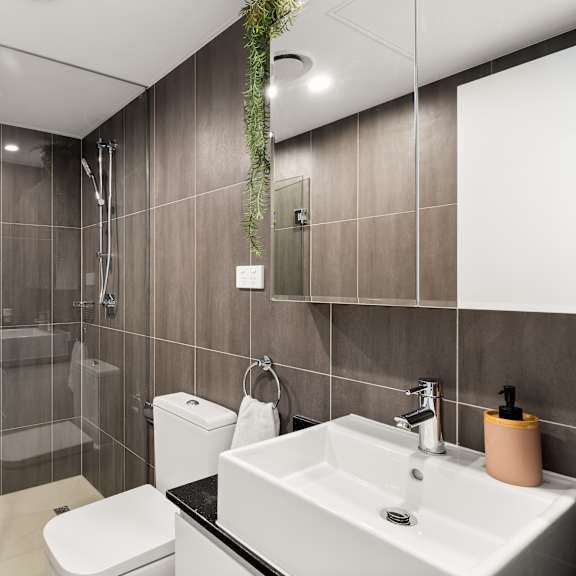 a bathroom with a white toilet, sink, and a glass shower stall.