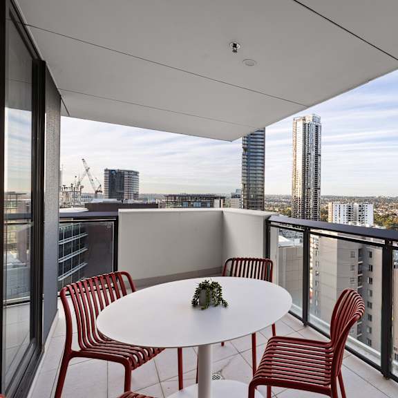 a balcony with a table and chairs overlooking a cityscape.