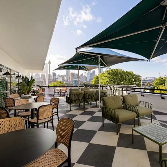 a patio with tables and chairs and a green umbrella.