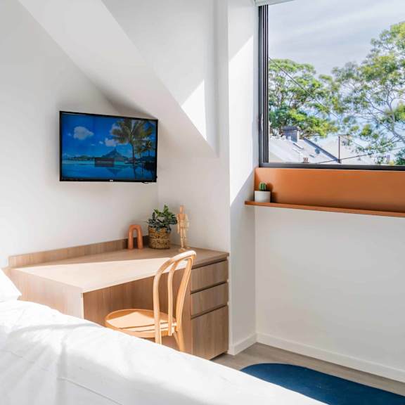 a bedroom with a bed and a desk and a window