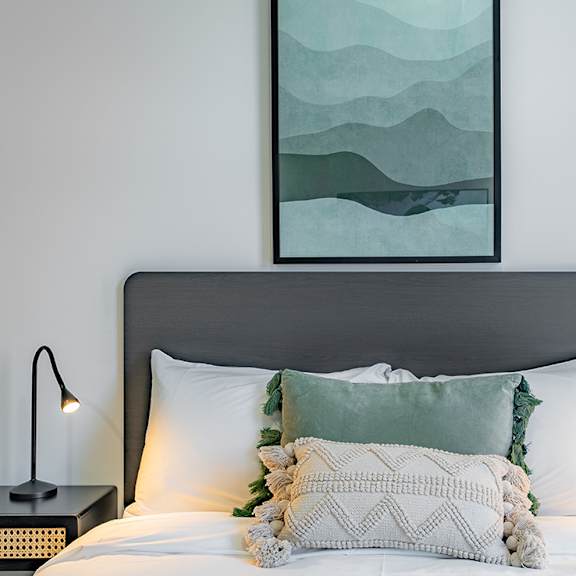 a bedroom with a bed with pillows and a painting on the wall