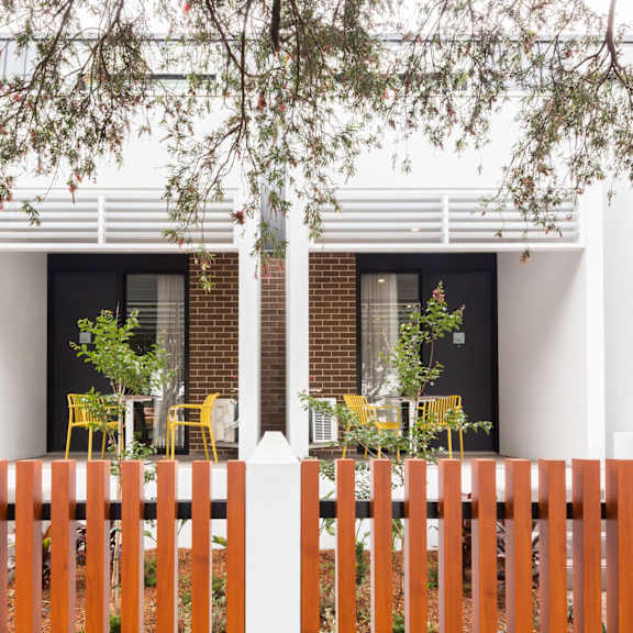 the exterior of a house with a fence and tables and chairs