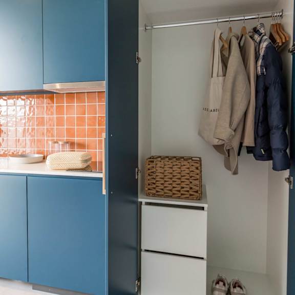 a kitchen with blue cabinets and a refrigerator and a closet