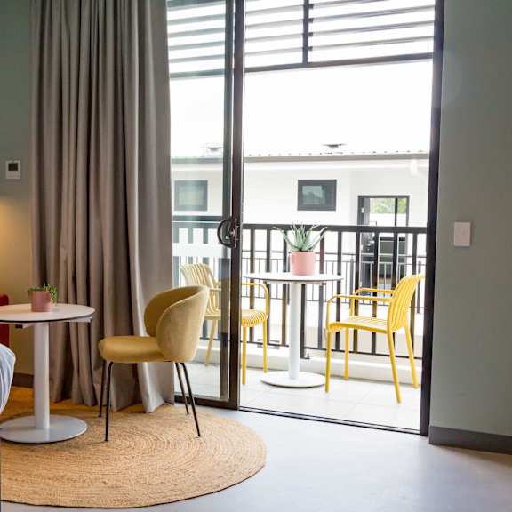 a hotel room with a bed and a balcony and a table and chairs