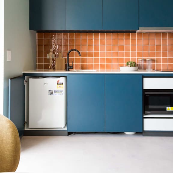 a small kitchen with blue cabinets and a white refrigerator