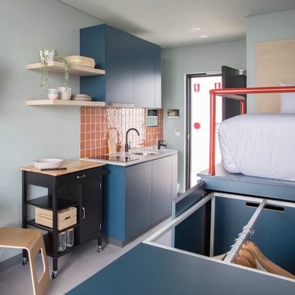 a small kitchen with a bed and a table in a small room