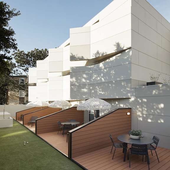 a terrace with a table and chairs in front of a white building