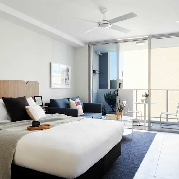 a bedroom with a bed and a living room with a balcony