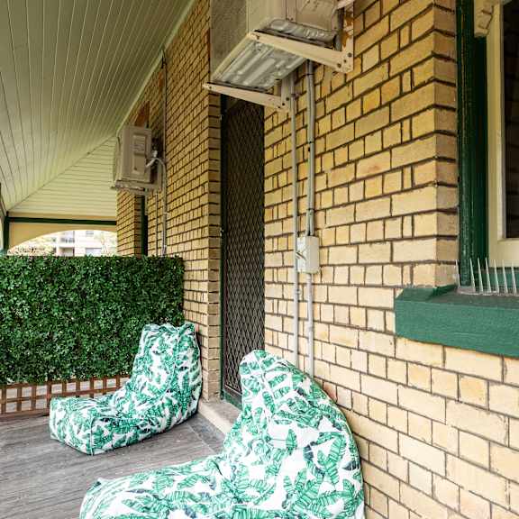two chairs sitting on a porch next to a brick building