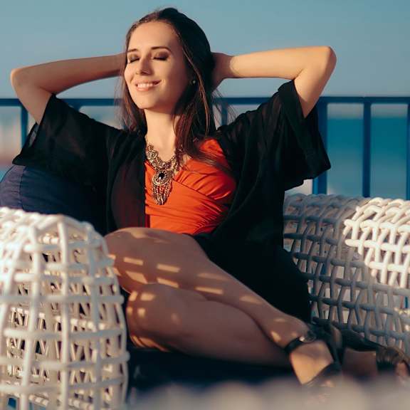 a woman sitting on a couch with her hands behind her head
