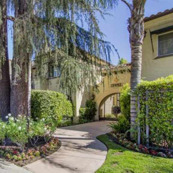 the front of a house with trees and a sidewalk