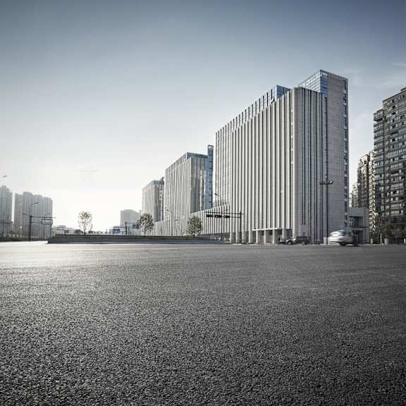 a black and white photo of a large empty square with tall buildings in the background