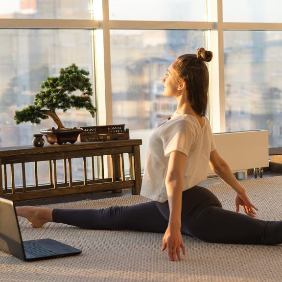 a woman in a white shirt and black pants does yoga on the floor in front of a