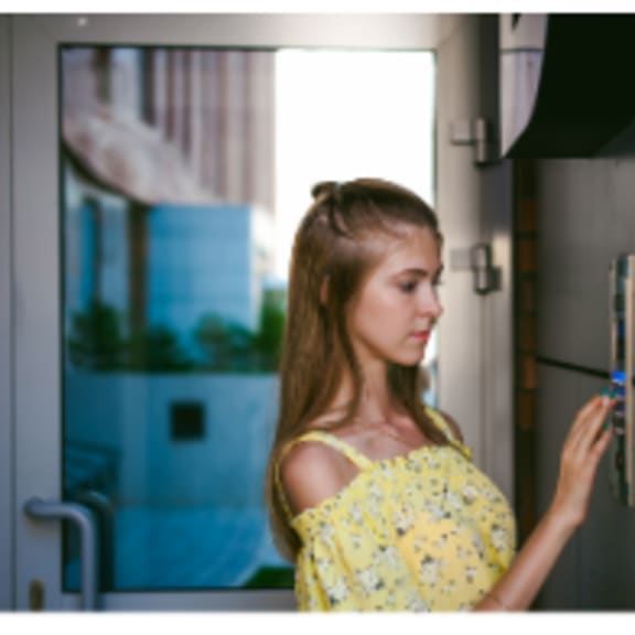 alt - a women trying to open the apartment door with a controlled access system