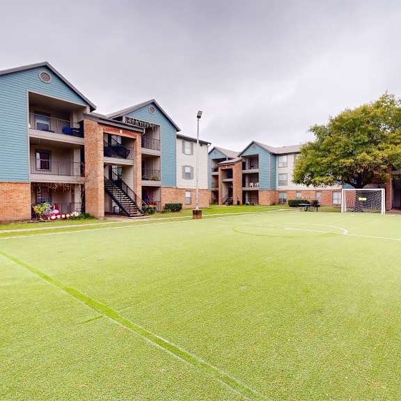 a grassy area in front of apartment buildings.