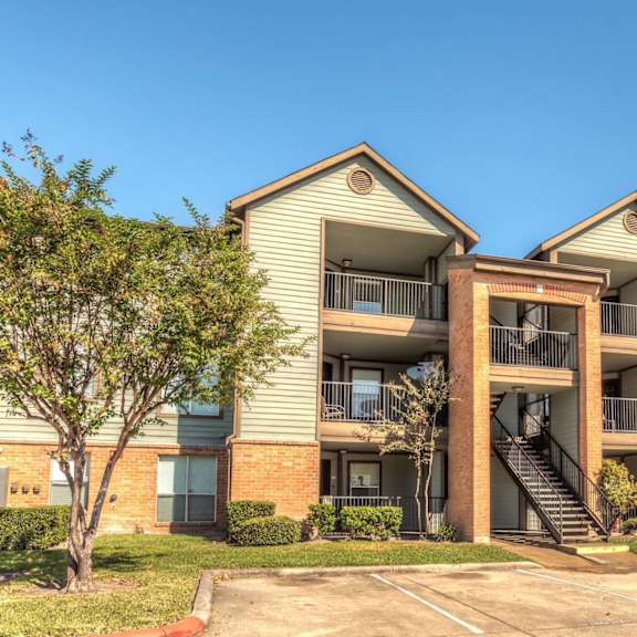 a large apartment complex with a parking lot in front.