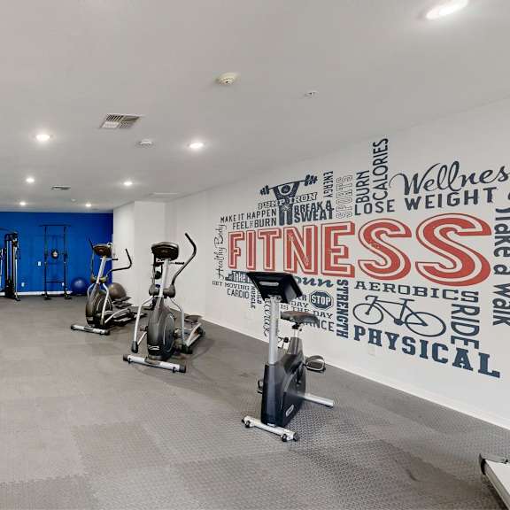 a gym with a variety of equipment including a treadmill, exercise bike, and weights.