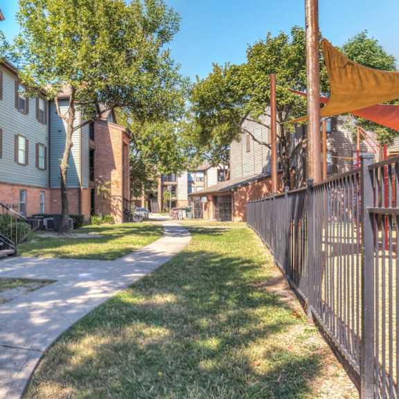 a sunny day in a residential area with apartment buildings and a pathway.