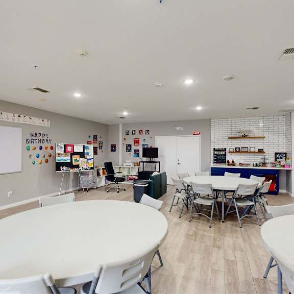 a room with tables and chairs and a whiteboard with the words "happy birthday" written on it.