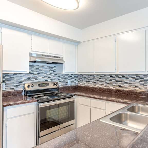 a kitchen with white cabinets and a stove top oven.