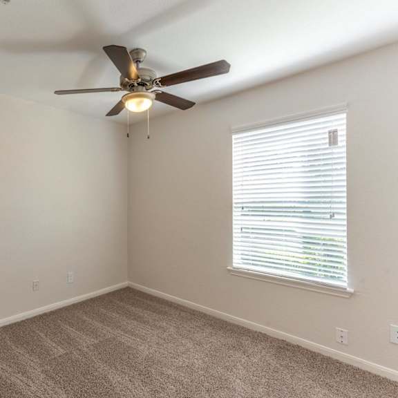 a room with a ceiling fan and a window with blinds.