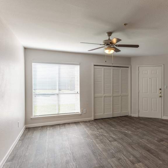 a room with a ceiling fan and a window with blinds.