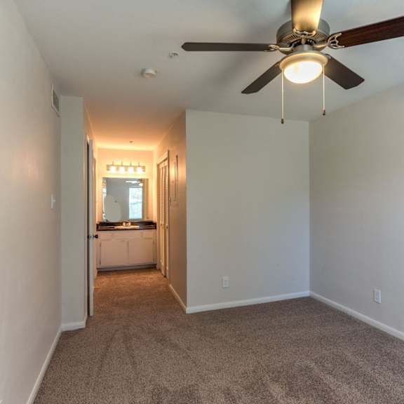 a room with a ceiling fan and carpeted floor.