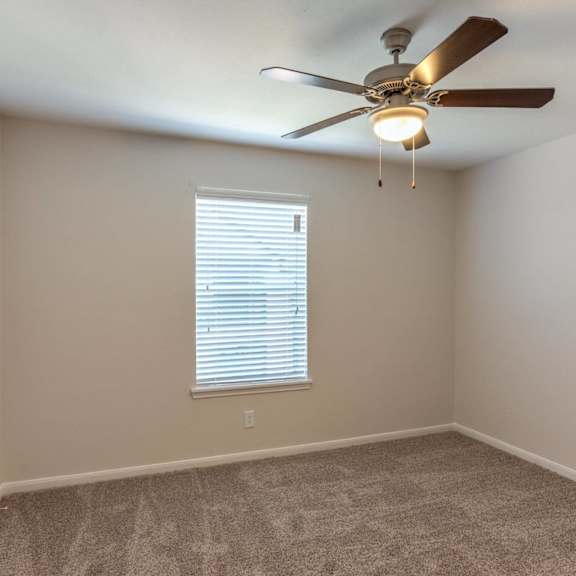 a room with a ceiling fan and a window with blinds.