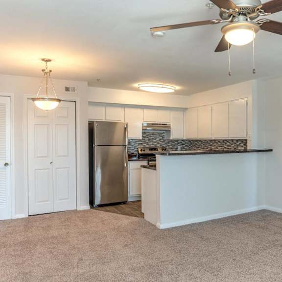 a kitchen with a refrigerator, cabinets, and a ceiling fan.