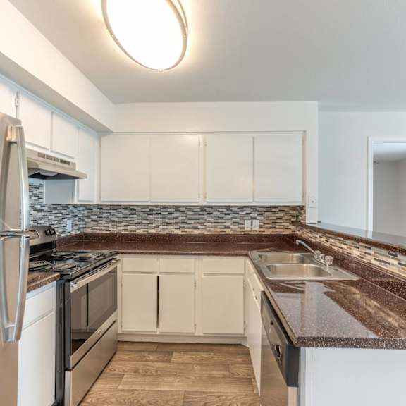a kitchen with a refrigerator, oven, and sink.