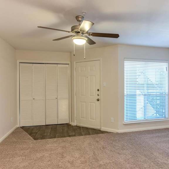 a room with a ceiling fan and a window with blinds.