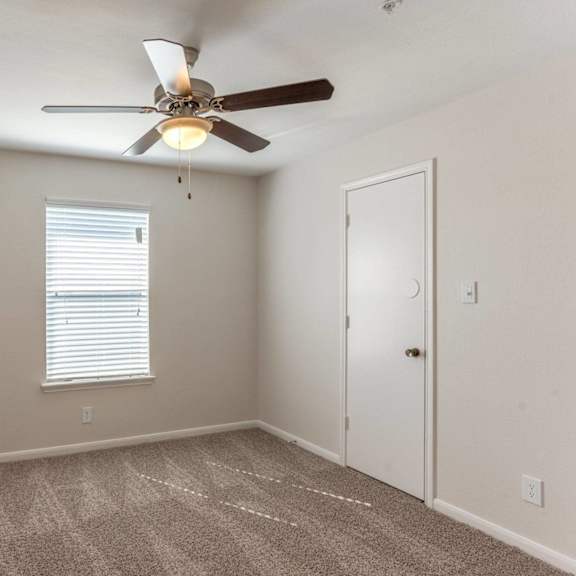 a room with a ceiling fan and carpeted floor.