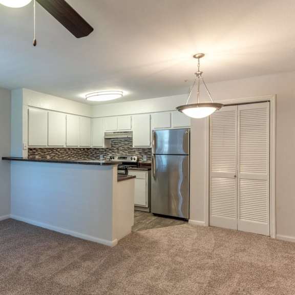 a kitchen area with a refrigerator, sink, and cabinets.