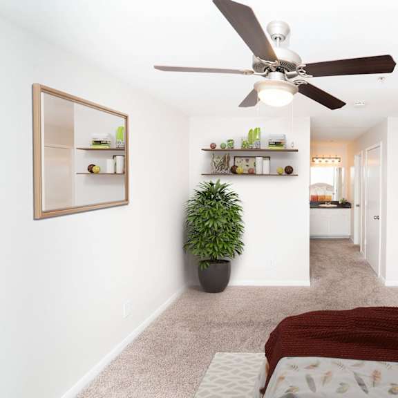 a bedroom with a bed, a ceiling fan, and a potted plant.