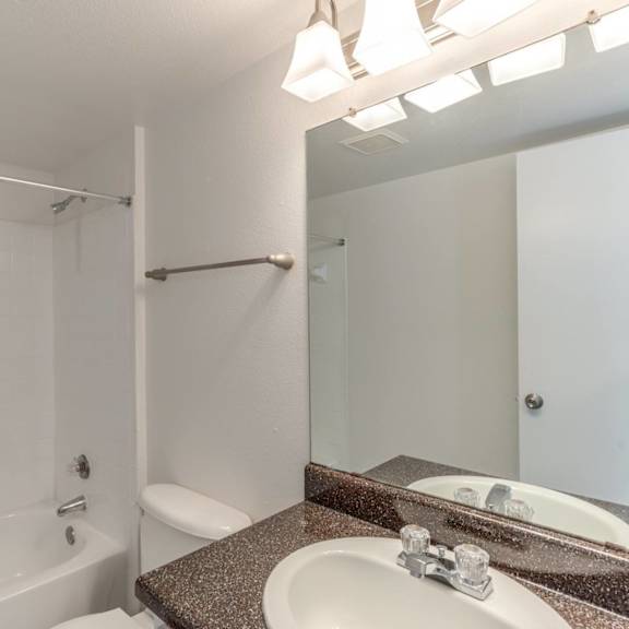 a white bathroom with a tub, sink, and mirror.
