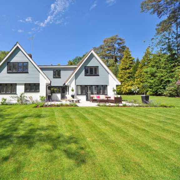 a house with a large lawn and a blue sky