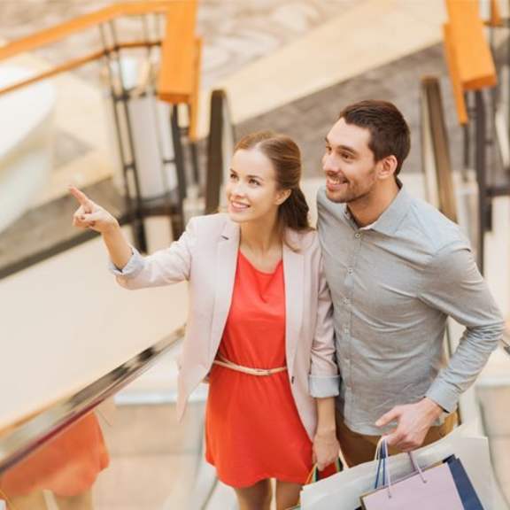 a man and woman walking down an escalator with shopping bags