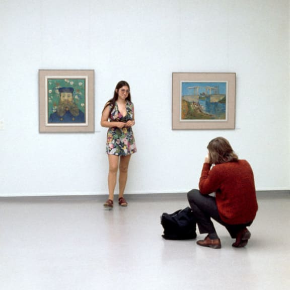 a woman is looking at two paintings in a museum