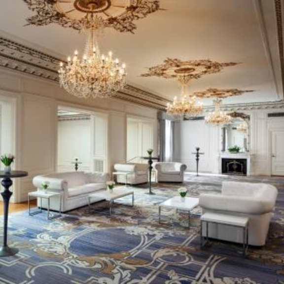 a luxurious living room with a chandelier, sofas, and a patterned rug.