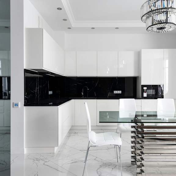 a modern kitchen with black and white cabinetry and a glass table.
