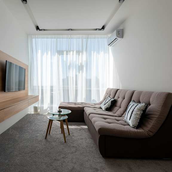 a modern living room with a brown sofa and a wooden entertainment unit.