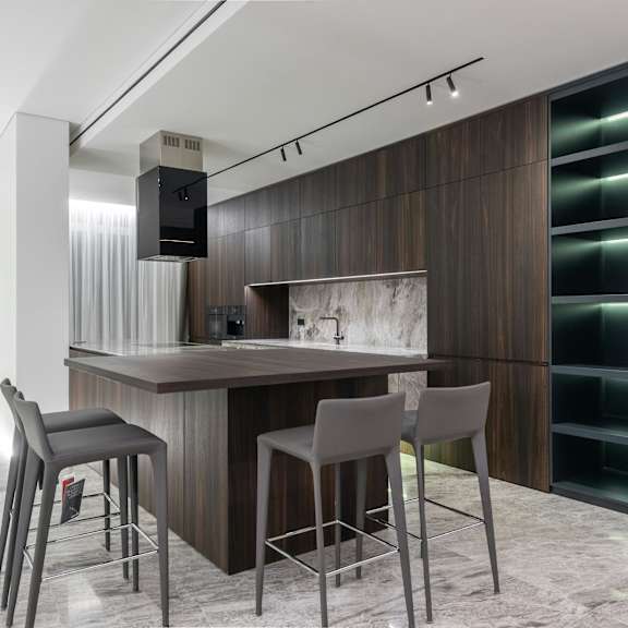 a modern kitchen with a bar area and grey chairs.
