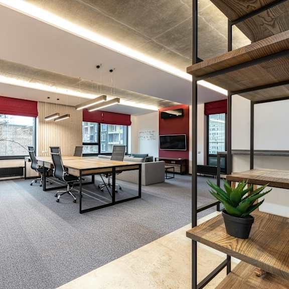 a modern office space with desks, chairs, and a plant.