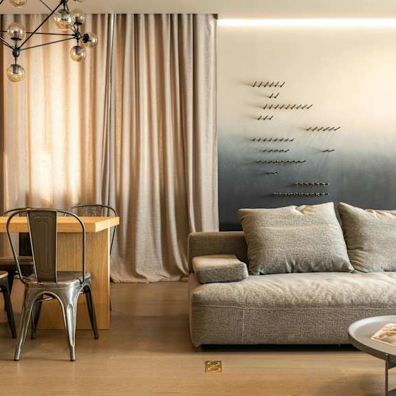 a modern living room with a grey couch, a wooden table, and a metal chair.
