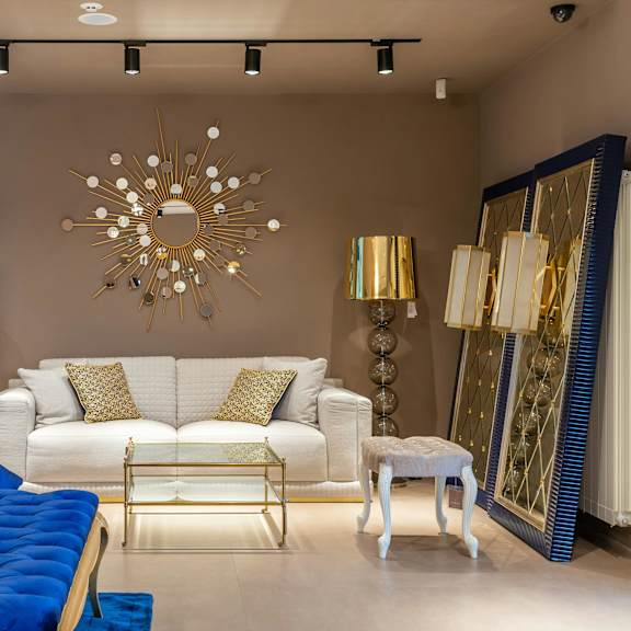 a living room with a white couch and a blue tufted bench.