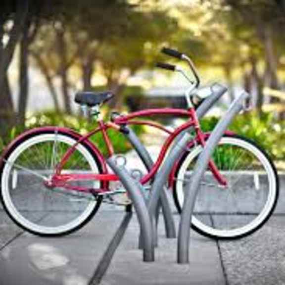 a red bicycle is parked on a grey bike rack.