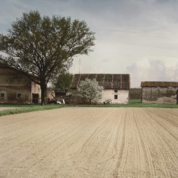 a dirt field in front of some old buildings