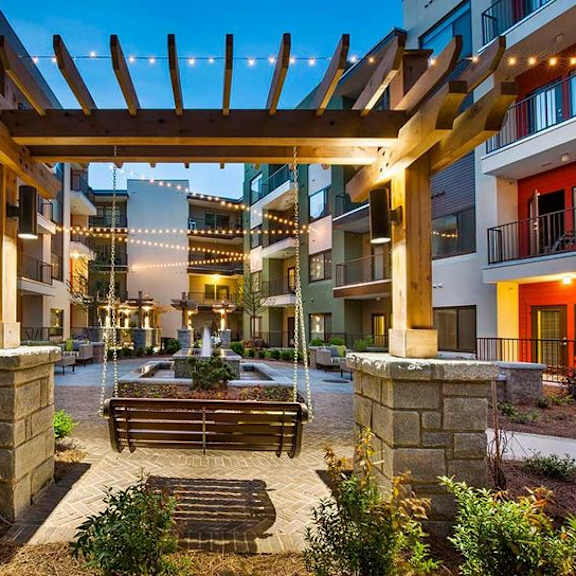 a wooden pergola is over a bench in a courtyard.